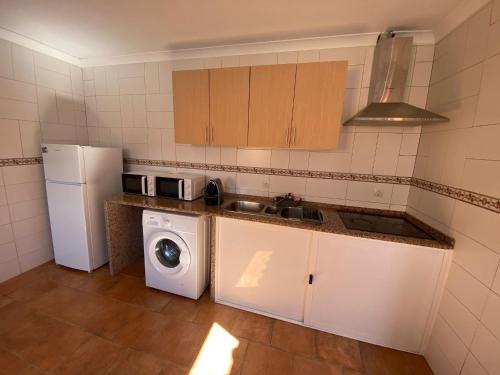 a kitchen with a refrigerator and a washing machine at Casa dos Diogos II in Grândola