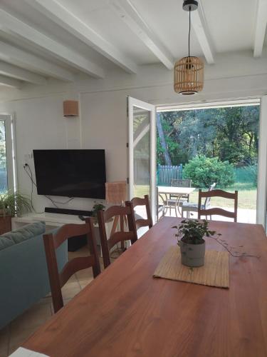 une salle à manger avec une table, des chaises et une télévision dans l'établissement Chalet proche océan, à Ondres