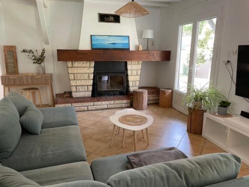 un salon avec un canapé et une cheminée dans l'établissement Chalet proche océan, à Ondres