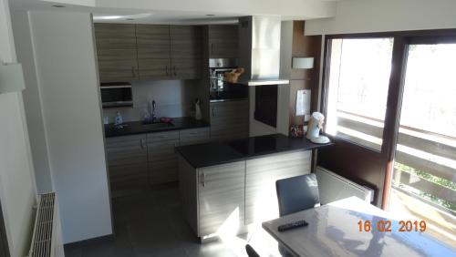 une cuisine avec des armoires en bois, une table et une fenêtre dans l'établissement Le Tavaillon, au Grand-Bornand