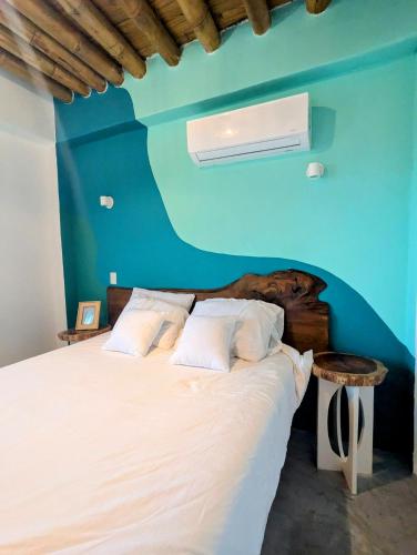 a bedroom with a bed with a blue wall at Wander Boutique Hotel in El Paredón Buena Vista