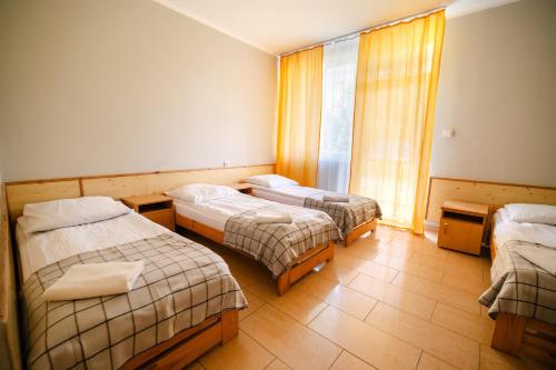 a hotel room with three beds and a window at Hotel Ameliówka in Masłów
