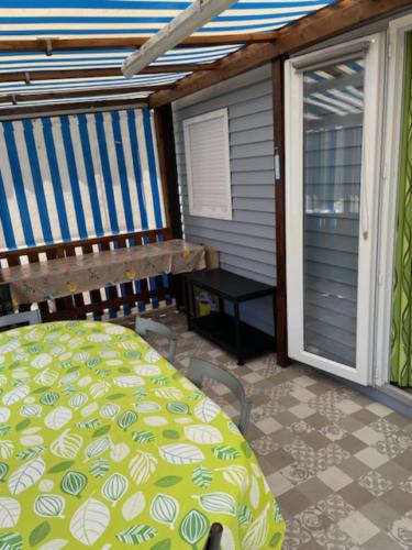 une véranda avec une moustiquaire, un lit et une table dans l'établissement Mobil-home Kapa - proche mer, à Les Moutiers