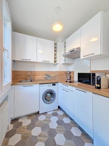 une cuisine avec des armoires blanches et une machine à laver dans l'établissement Appartement confortable et calme à Tours centre, à Tours