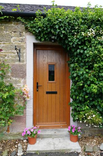 a wooden door in a stone building with flowers at Country Cottage on Private Estate in Minishant