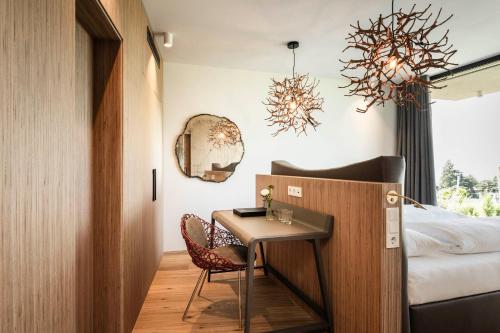 a room with a bed and a table and a chair at Hotel Mitterplatt (Schenna Resort) in Schenna