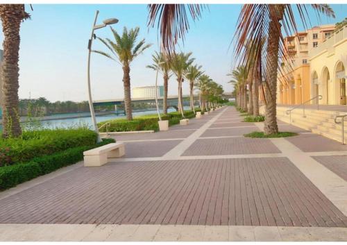 a sidewalk with palm trees next to a river at Eleganza Marina Apartments KAEC in King Abdullah Economic City