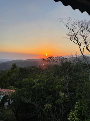 a sunset from the top of a hill with trees at Casa de montaña con vista al océano pacífico in Magallanes