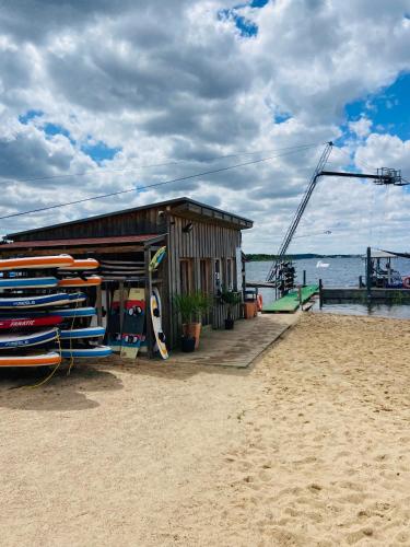 a building on the beach with surfboards in front of it at 8 Personen Ferienhaus ,,Seegelblick" am Goitzschesee, erste Reihe am Strand mit Sauna, Kamin, Wallbox & SUP in Pouch