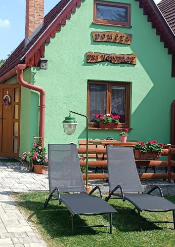 two chairs sitting in front of a green building at Domček pri vodopáde in Lúčky