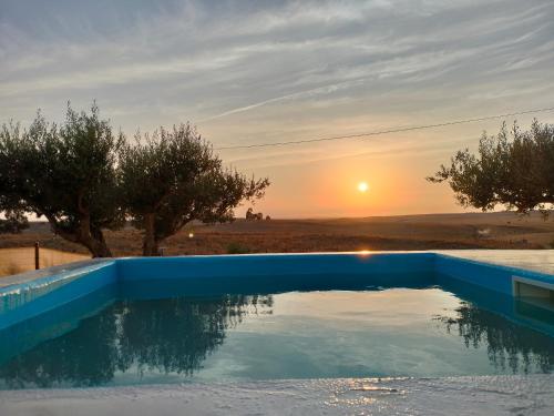 a swimming pool with a sunset in the background at Canto da Planície in Conceição