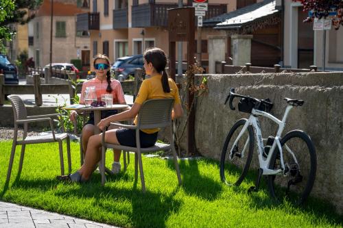two women sitting at a table in the grass at Chalet Silvi Residence in Bormio