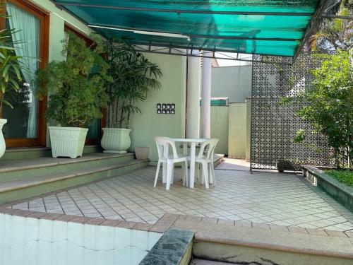 a patio with two white chairs and a table at Mansão Adalgisa in Osasco