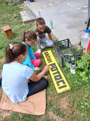 a woman and two children playing with a garden sign at Dulović - KATUN POTOCI in Kolašin