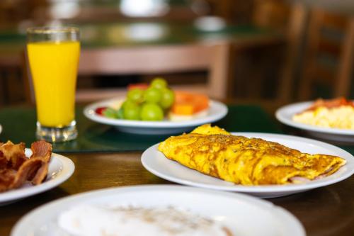 a table with plates of food and a glass of orange juice at Hotel Golden Park All Inclusive Poços de Caldas By Nacional Inn in Poços de Caldas