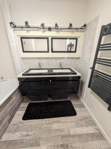 La salle de bains est pourvue d'une baignoire noire et d'un lavabo. dans l'établissement Studio Marcel D tout confort, à Saint-Vigor-le-Grand