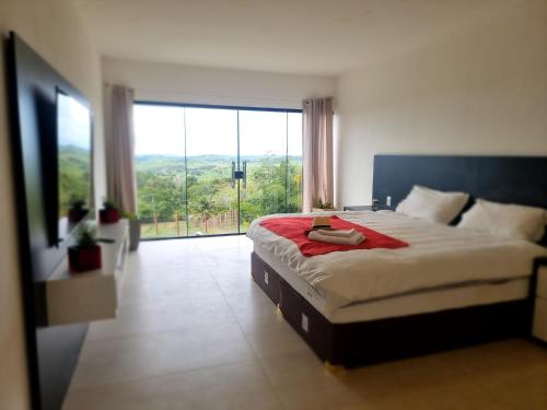 a bedroom with a large bed with a large window at Fazenda de Jehne in Camamu