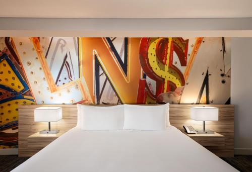 a bedroom with a large white bed with a mural at The LINQ Hotel & Casino, A Caesars Destination in Las Vegas