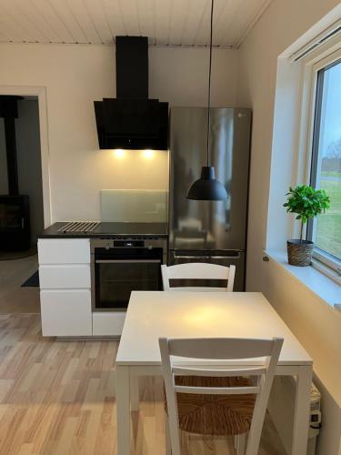 a kitchen with a table and chairs and a refrigerator at Lejlighed i naturskønt område in Bratten Strand