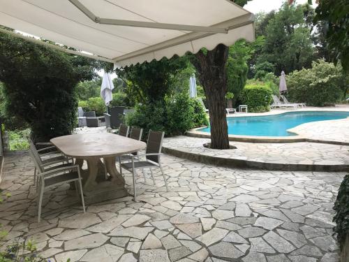 un patio avec une table et des chaises et une piscine dans l'établissement Villa Souleiadito dans le Golfe de Saint Tropez, au Plan-de-la-Tour