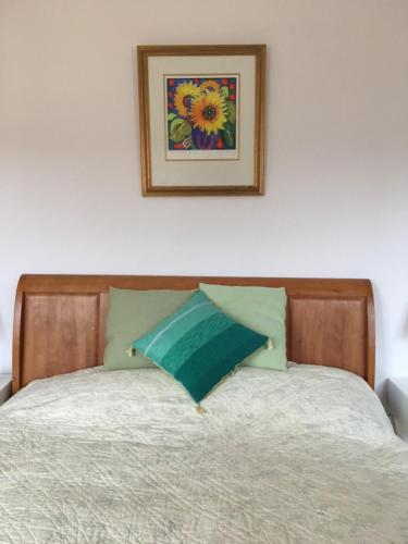 a bed with a wooden head board and a picture on the wall at The Old Dairy (Chute Forest) in Andover