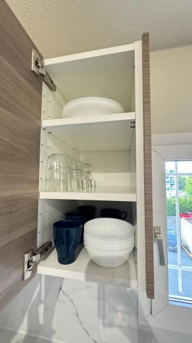 d'une armoire blanche avec plaques et bols dans l'établissement Frejus Plage F1 bis La Miougrano, à Fréjus