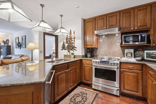 a kitchen with wooden cabinets and a stove top oven at Ascent 203 by East West Hospitality in Avon
