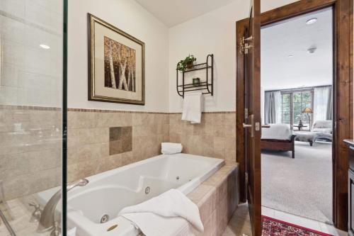 a bathroom with a bath tub in a room at Ascent 203 by East West Hospitality in Avon