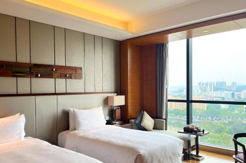 a hotel room with two beds and a large window at HUALUXE Yangjiang City Center in Yangjiang