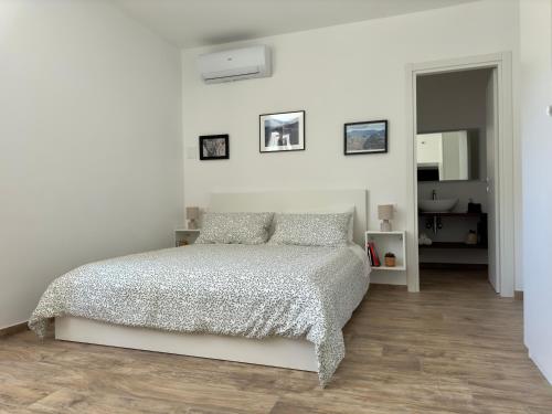 a white bedroom with a bed and a mirror at Pennadomo Climbing House in Pennadomo