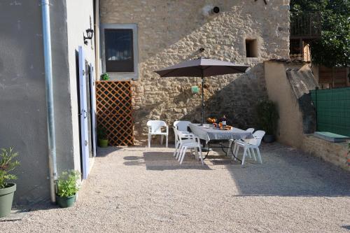 a patio with a table and chairs and an umbrella at Les Vignes du Luberon in Saignon