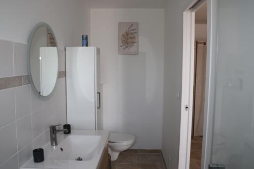 a white bathroom with a toilet and a sink at Les Vignes du Luberon in Saignon