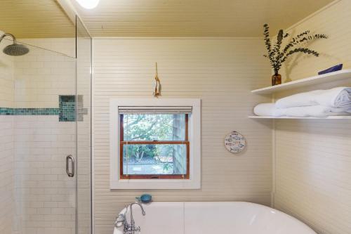 a bathroom with a tub and a shower and a window at Captain's Corner in Manzanita