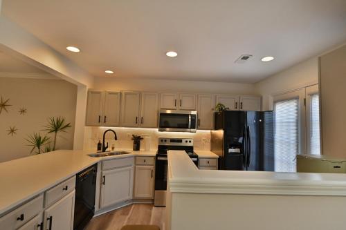 a kitchen with white cabinets and a black refrigerator at Amazing Renovated Townhouse in Greensboro