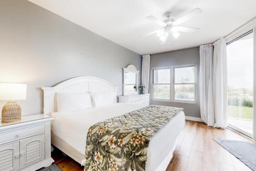 Un dormitorio blanco con una cama y un ventilador de techo. en Waters Edge 105, en Fort Walton Beach