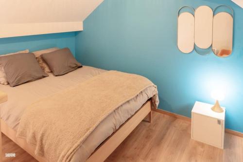 a bedroom with a bed and a blue wall at Hypercentre, calme, vintage - Le Rétro in Pontarlier
