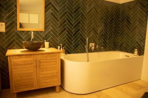 une salle de bain avec une baignoire, un lavabo et un miroir dans l'établissement Maison avec jardin, centre ville et plage à pieds, à Houlgate