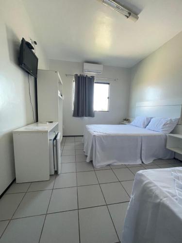 a hotel room with two beds and a television at Pousada Alvorada in Ubajara