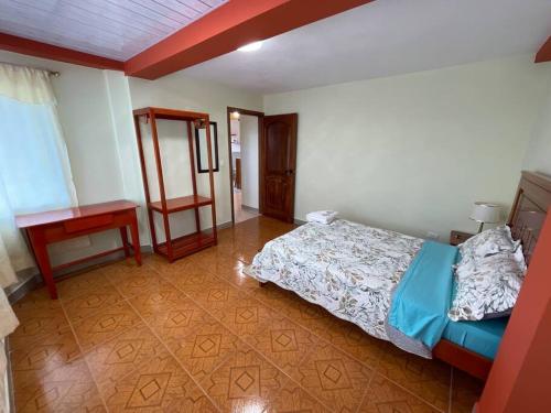 a bedroom with a bed and a table and a desk at Departamento Amazonia Ecuador in Puyo