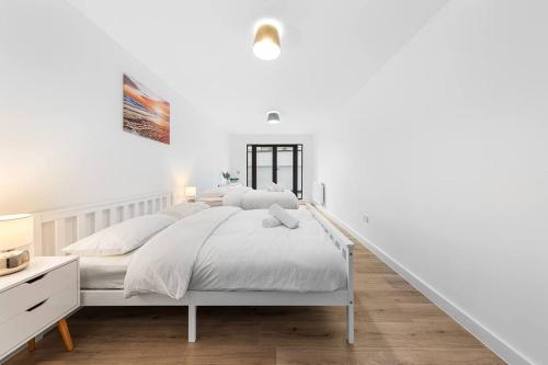 a white bedroom with a white bed and a staircase at Spacious Sleep 14 - 1 min from Tooting Station MR3 in London