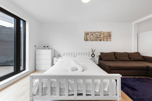 a white bedroom with a bed and a couch at Spacious Sleep 14 - 1 min from Tooting Station MR3 in London