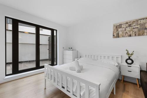 a bedroom with a white bed and a large window at Spacious Sleep 14 - 1 min from Tooting Station MR3 in London