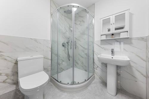 a bathroom with a shower and a toilet and a sink at Spacious Sleep 14 - 1 min from Tooting Station MR3 in London