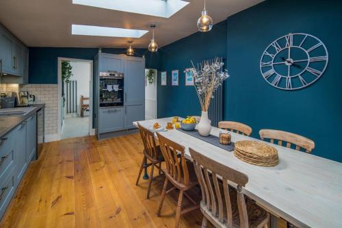a kitchen with a large table and a clock on the wall at Captain's Cottage - 1BR, Garden, 2-Min Walk to High St in Cowes