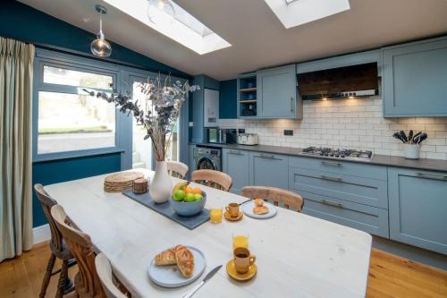 a kitchen with blue cabinets and a table with food on it at Captain's Cottage - 1BR, Garden, 2-Min Walk to High St in Cowes