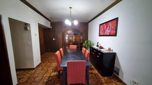 a dining room with a long table and red chairs at Gold House in Neuquén