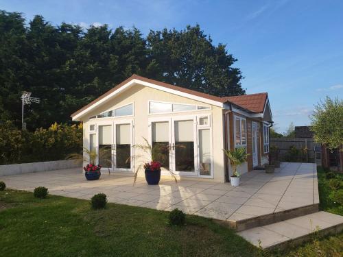 a small house with large windows on a patio at The Hilltop Bungalow in Clophill