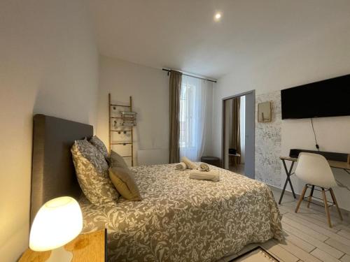 Un dormitorio con una cama, un escritorio y un televisor. en Joli appartement hypercentre T2, classé meublé de tourisme 3 avec parking gratuit, en Béziers