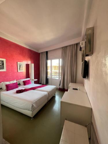 a bedroom with a large bed and a red wall at La Renaissance hôtel Marrakech in Marrakech