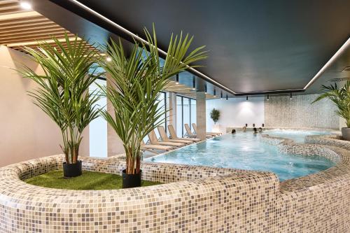 a large swimming pool with palm trees in a lobby at Baltic Waves Resort & Wellness I Where the Baltic Meets Luxury in Międzyzdroje